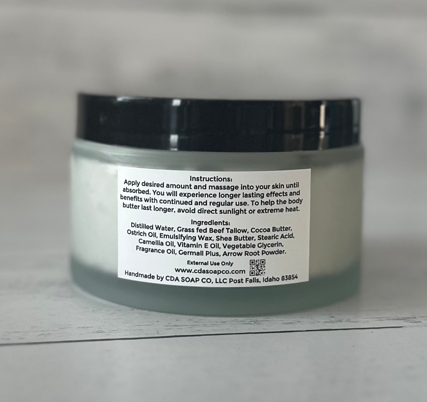 Jar of body butter with ingredient label on a gray background