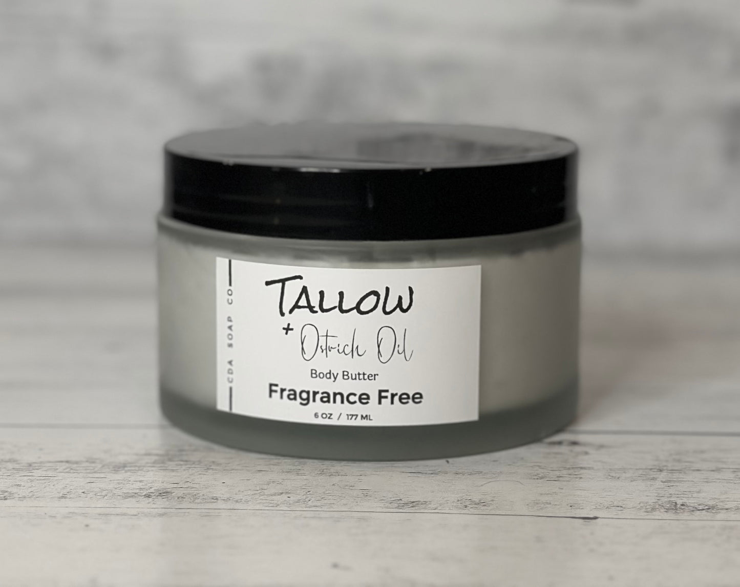 A jar of Tallow & Ostrich Oil Body Butter labeled 'FRAGRANCE FREE' on a wooden surface.