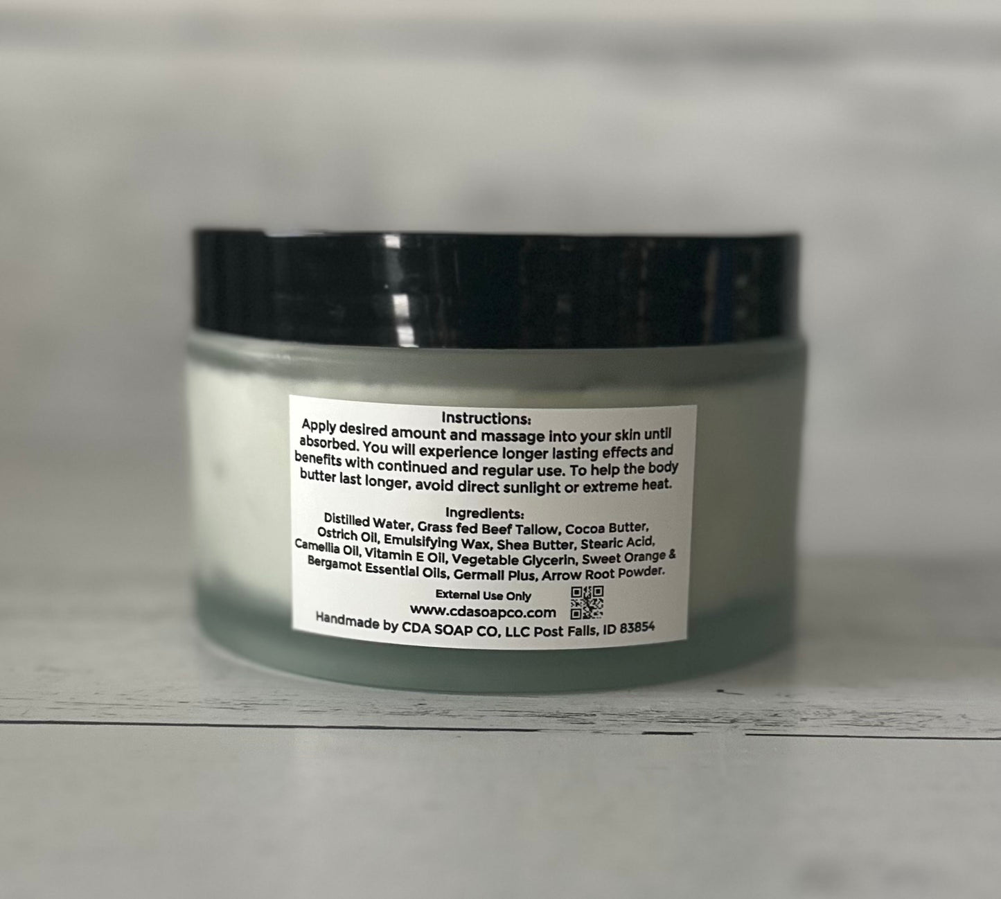 Jar of body butter with ingredient label on a gray background