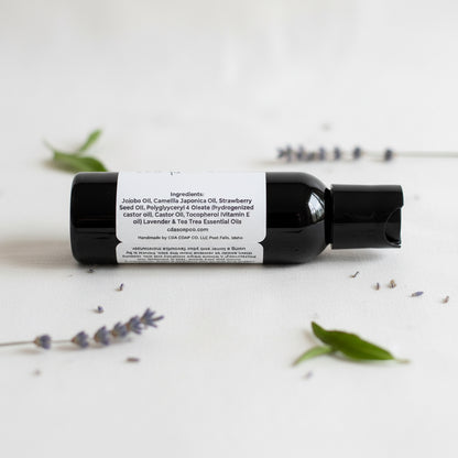 Black bottle with a label on a white background with lavender and green leaves.