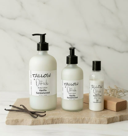 Three bottles of Tallow & Co. body lotion on a wooden board with vanilla beans and sandalwood on a light background.
