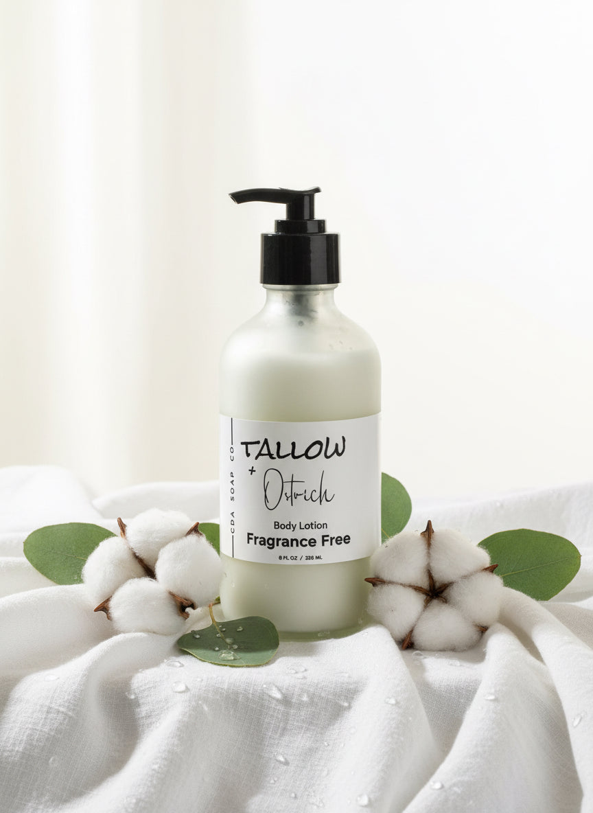 Tallow & Ostrich oil body lotion bottle on a white fabric background with cotton and leaves.