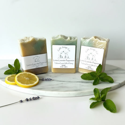 Three soaps on a marble tray with lemon slices and mint leaves on a white background