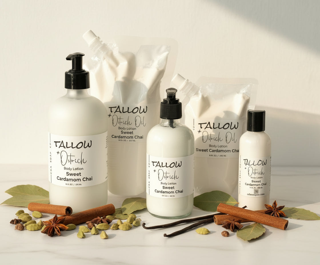 Bottles of Tallow + Ostrich Oil body lotion on a white surface with spices and leaves.