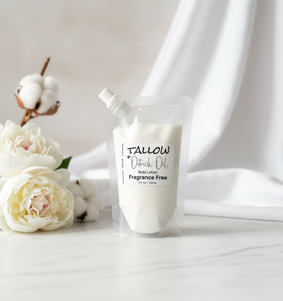 Body lotion in plastic pouch with a spout with 'Tallow + Oatrich Oil' label on a wooden surface