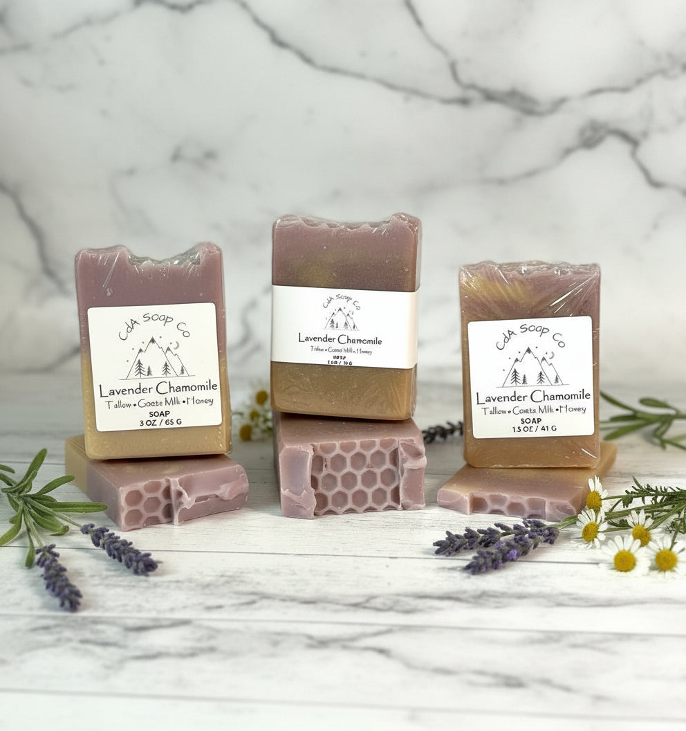 Three bars of lavender chamomile soap with packaging on a marble surface.
