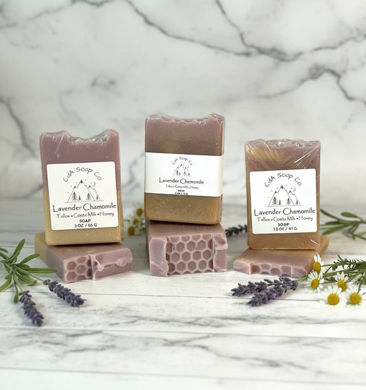 Three bars of lavender chamomile soap with packaging on a marble surface.