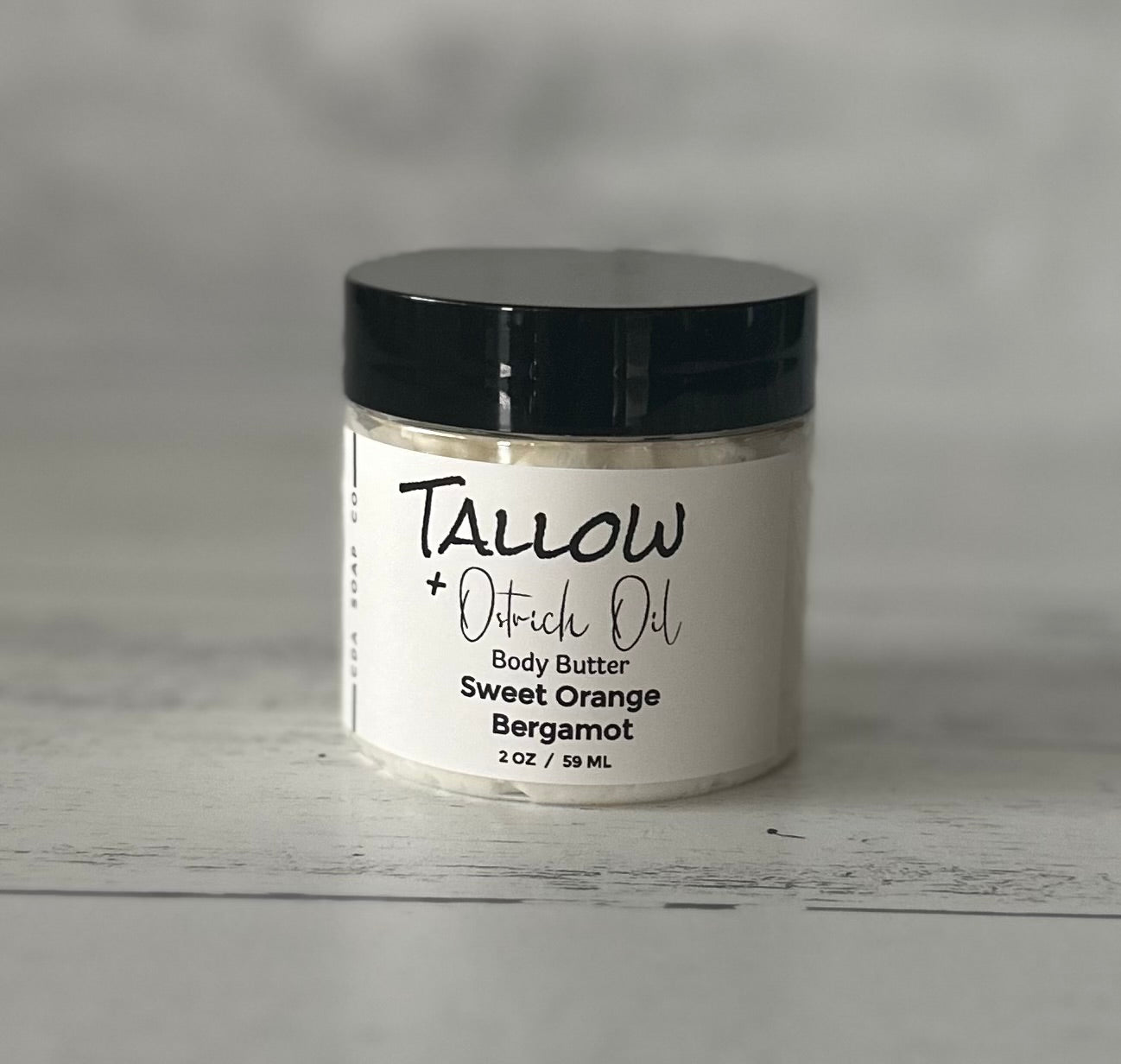 Small Jar of Tallow + Ostrich Oil body butter with a black lid on a gray background