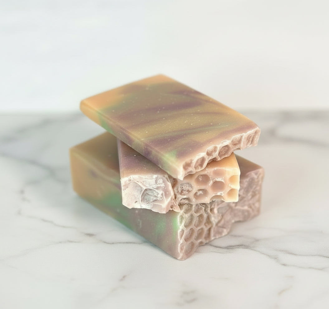 Three bars of multicolored soap stacked on a light surface 