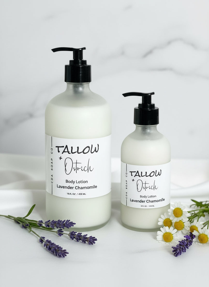 Two bottles of Tallow & Ostrich body lotion on a white fabric background with lavender and chamomile flowers.