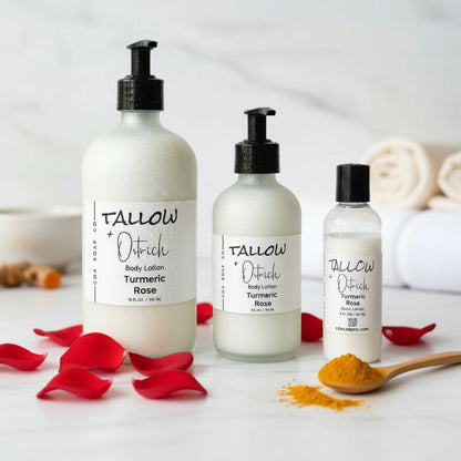 Three bottles of Tallow + Ostrich body lotion on a white surface with turmeric roots and rose petals.