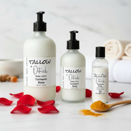 Three bottles of Tallow + Ostrich body lotion on a white surface with turmeric roots and rose petals.