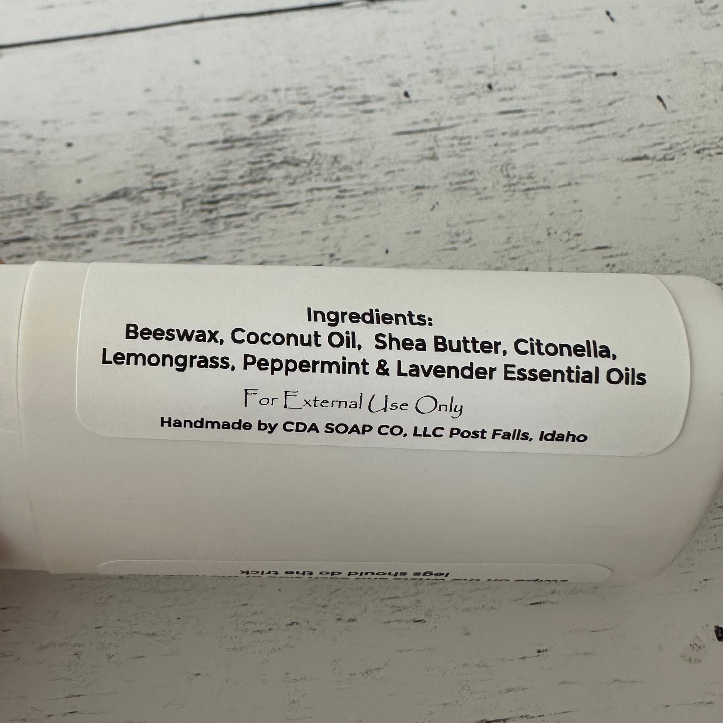 White contsiner with label detailing ingredients on a wooden surface.