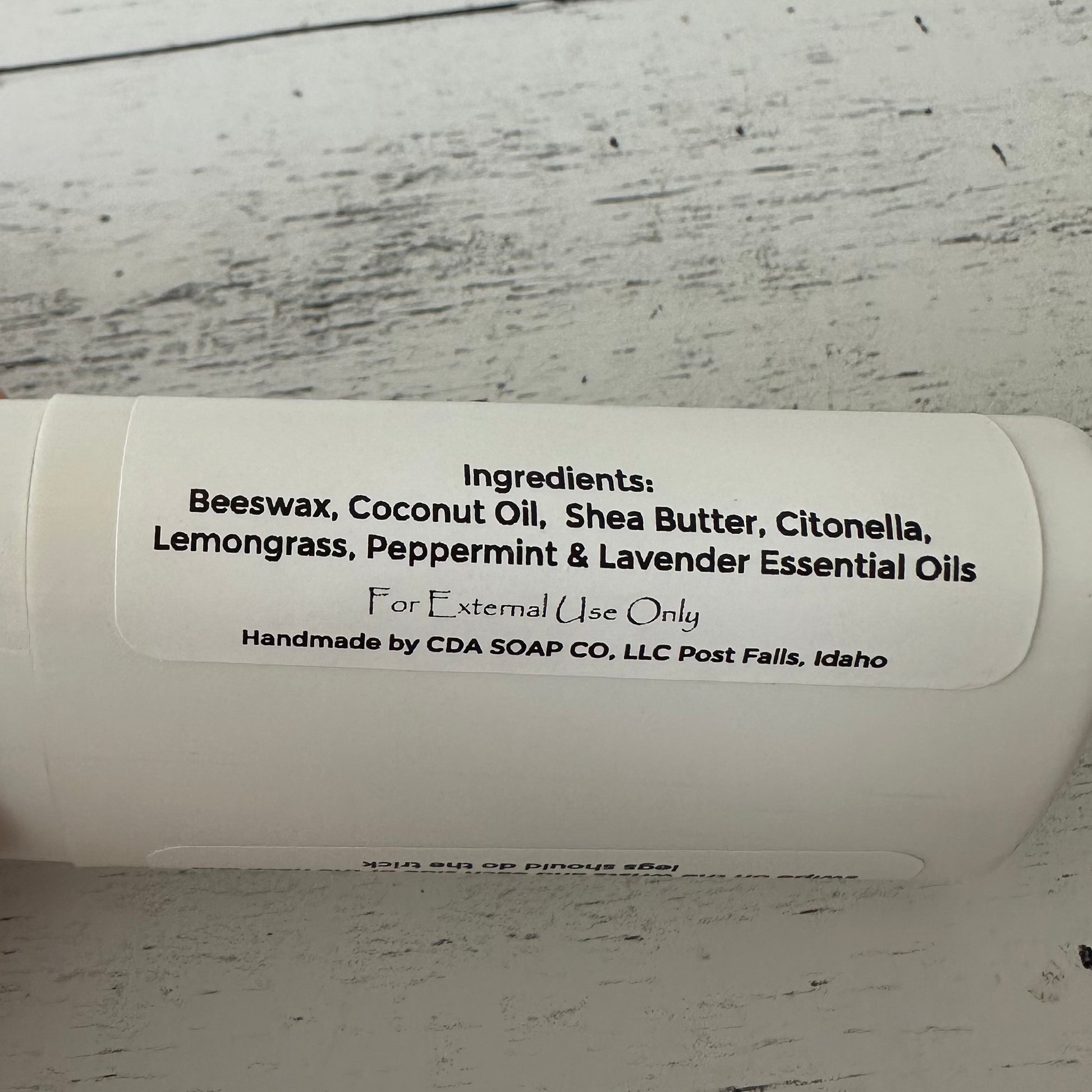 White contsiner with label detailing ingredients on a wooden surface.