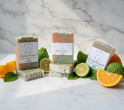 Orange Bergamot soap bars with packaging on a marble surface with citrus fruits.