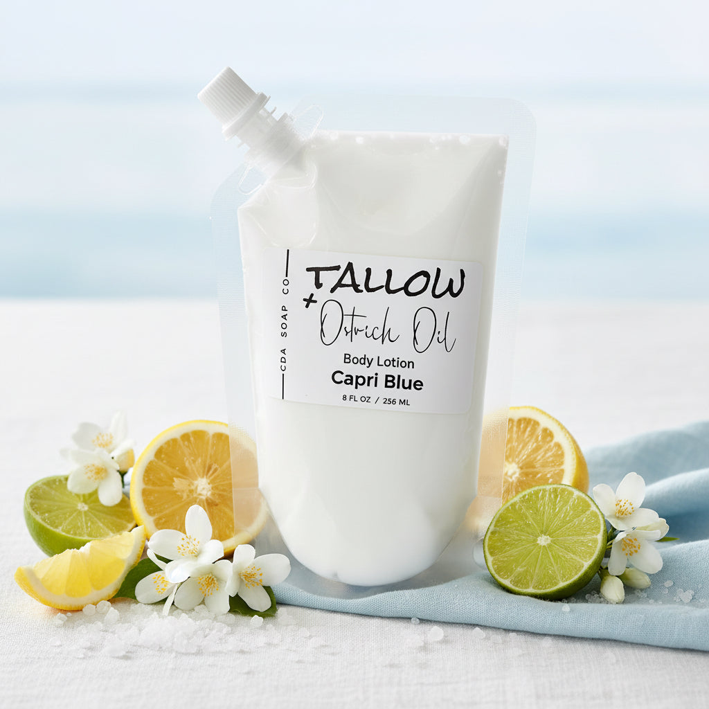 Body lotion bag with 'Tallow + Ostrich ' branding surrounded by lemons and limes on a sandy background