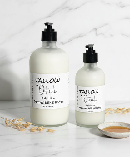 Two bottles of Tallow + Ostrich body lotion on a marble surface with oatmeal and honey.