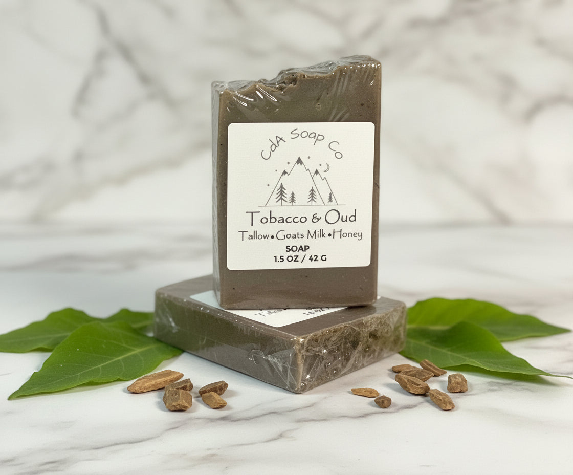 Bar of soap with packaging labeled 'Tobacco & Oud' on a wooden surface with leaves and seeds.
