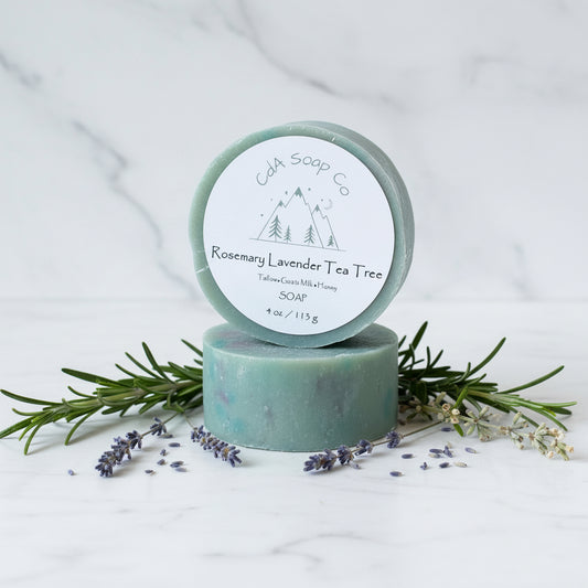 Two bars of soap with a visible brand label on a white background with lavender and rosemary.