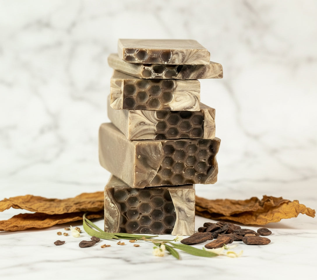 Stack of honeycomb-patterned soap bars with dried herbs and seeds on a white background