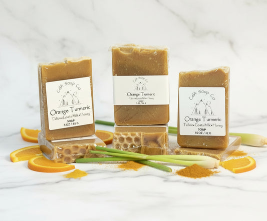 Three bars of Orange Turmeric soap with visible labels on a white background.