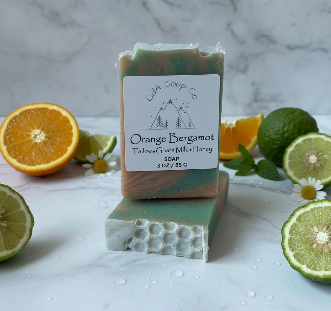 Bar of soap with 'CDA Soap Co' label surrounded by citrus fruits and herbs on a marble surface