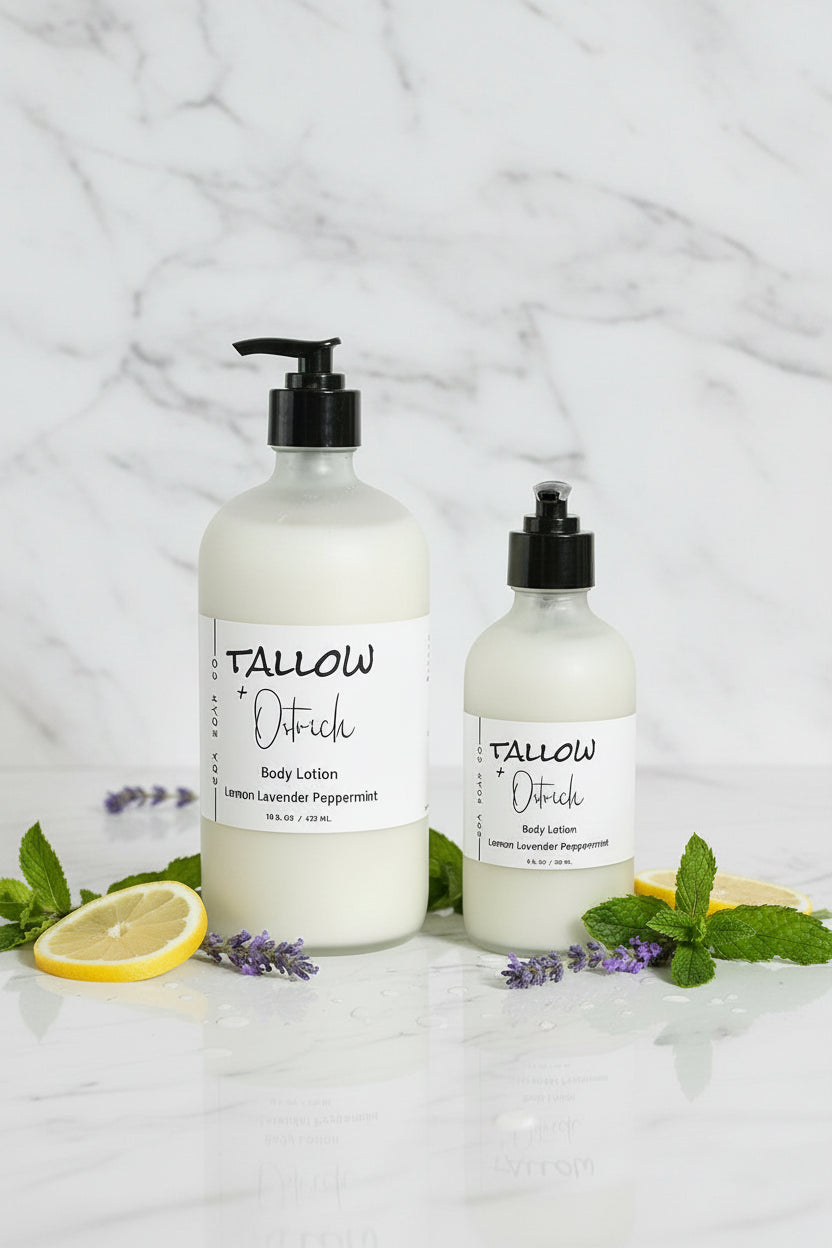 Two bottles of Tallow & Oatflesh body lotion on a white surface with lemons and mint leaves.