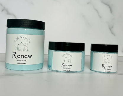 Three jars of 'Renew' skin cream on a marble surface with a light gray background.