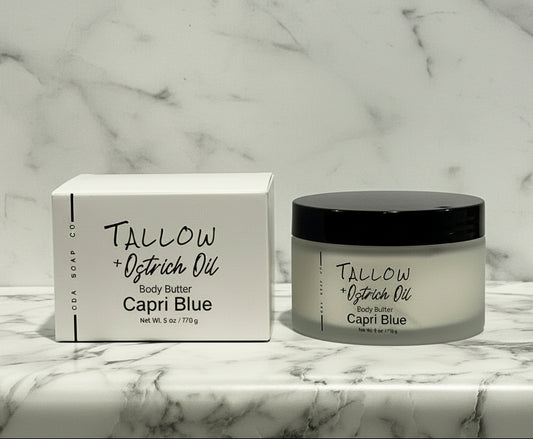 Capri Blue Tallow + Ostrich Oil body butter jar and box on a marble surface with wooden background