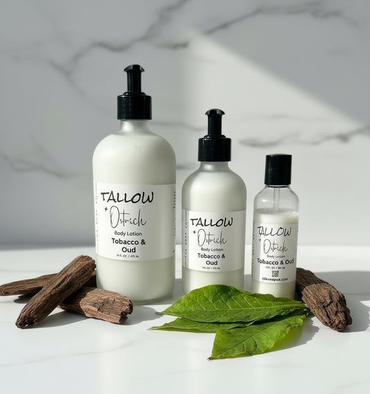 Three bottles of Tallow & Ostrich body lotion on a white surface with leaves and wood.
