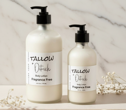 Two bottles of Tallow & Ostrich body lotion on a marble surface with flowers.