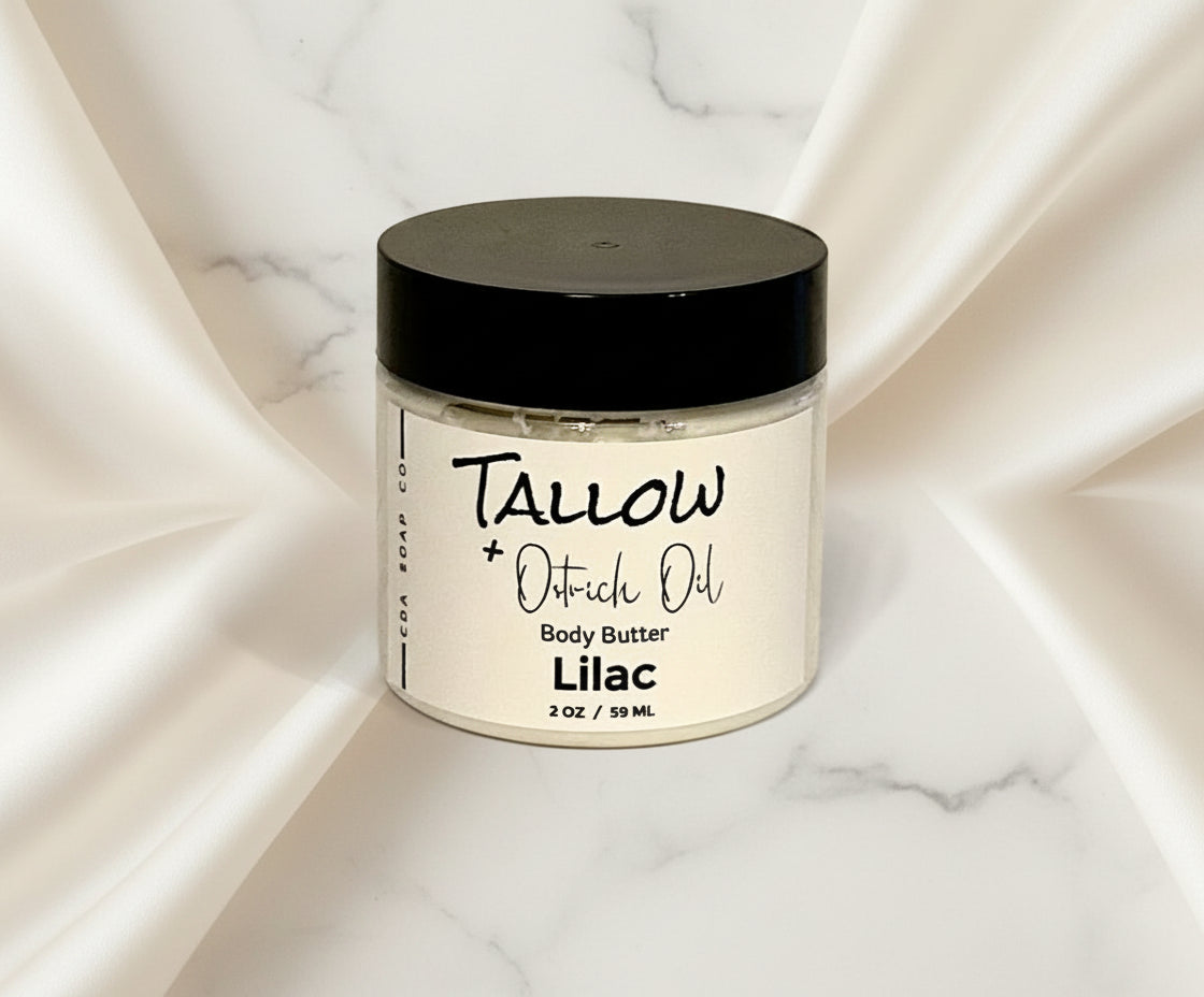 A frosted white glass jar with a black lid labeled 'Tallow Ostrich Oil Body Butter Lilac'.