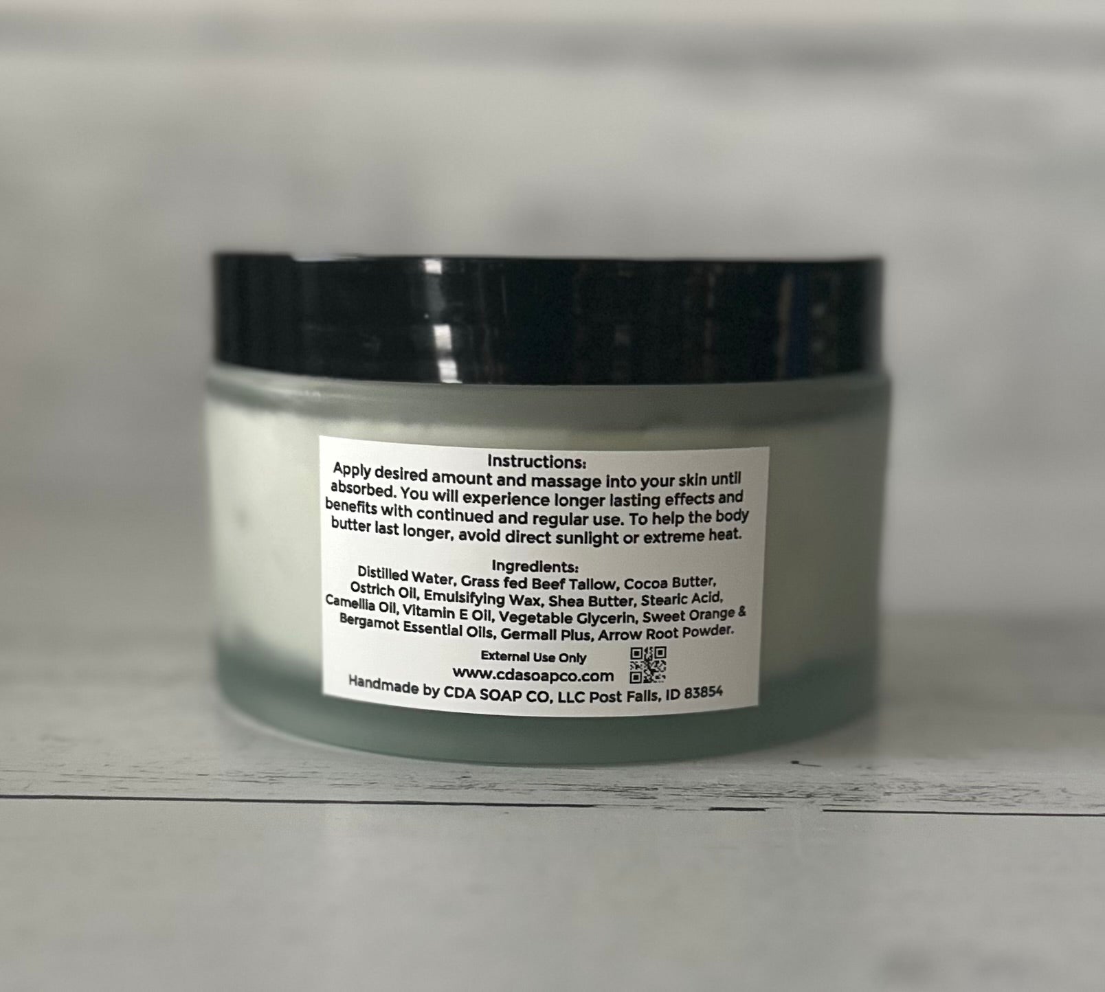 Jar of body butter  with ingredient label on a gray background