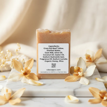 Bar of soap with a label displaying ingredients on a marble surface with flowers.