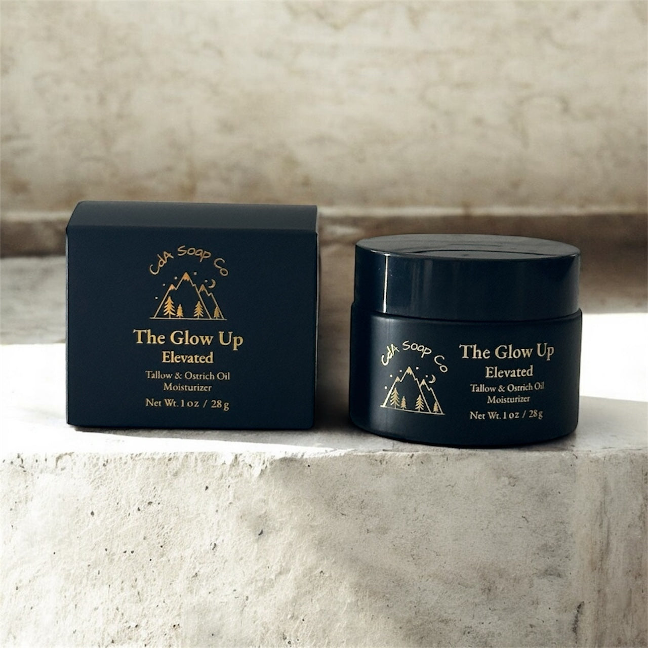 Black jar and box of 'The Glow Up Elevated' product on a stone surface with a neutral background