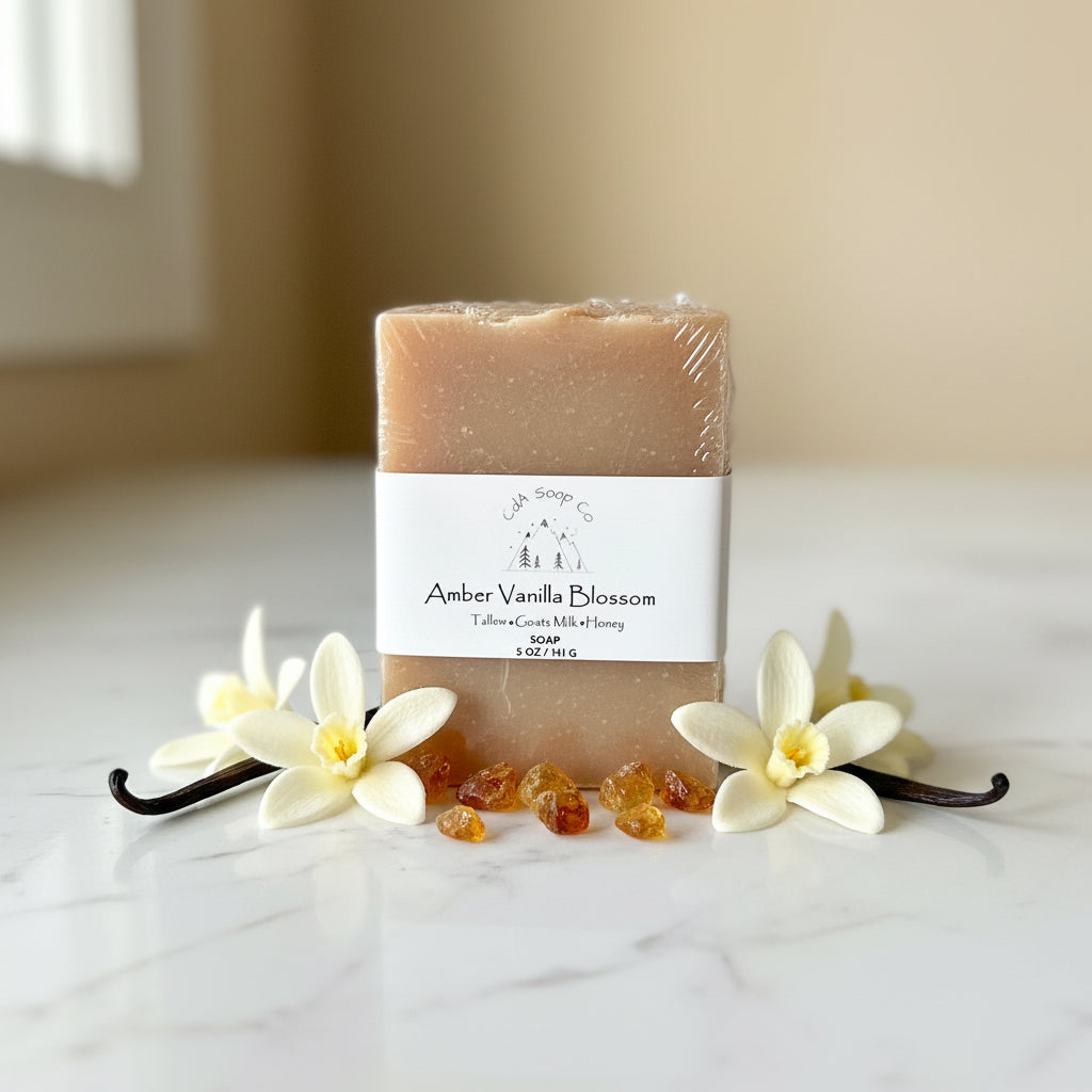 Bar of soap with 'Amber Vanilla Blossom' label surrounded by vanilla flowers and pods on a light surface.