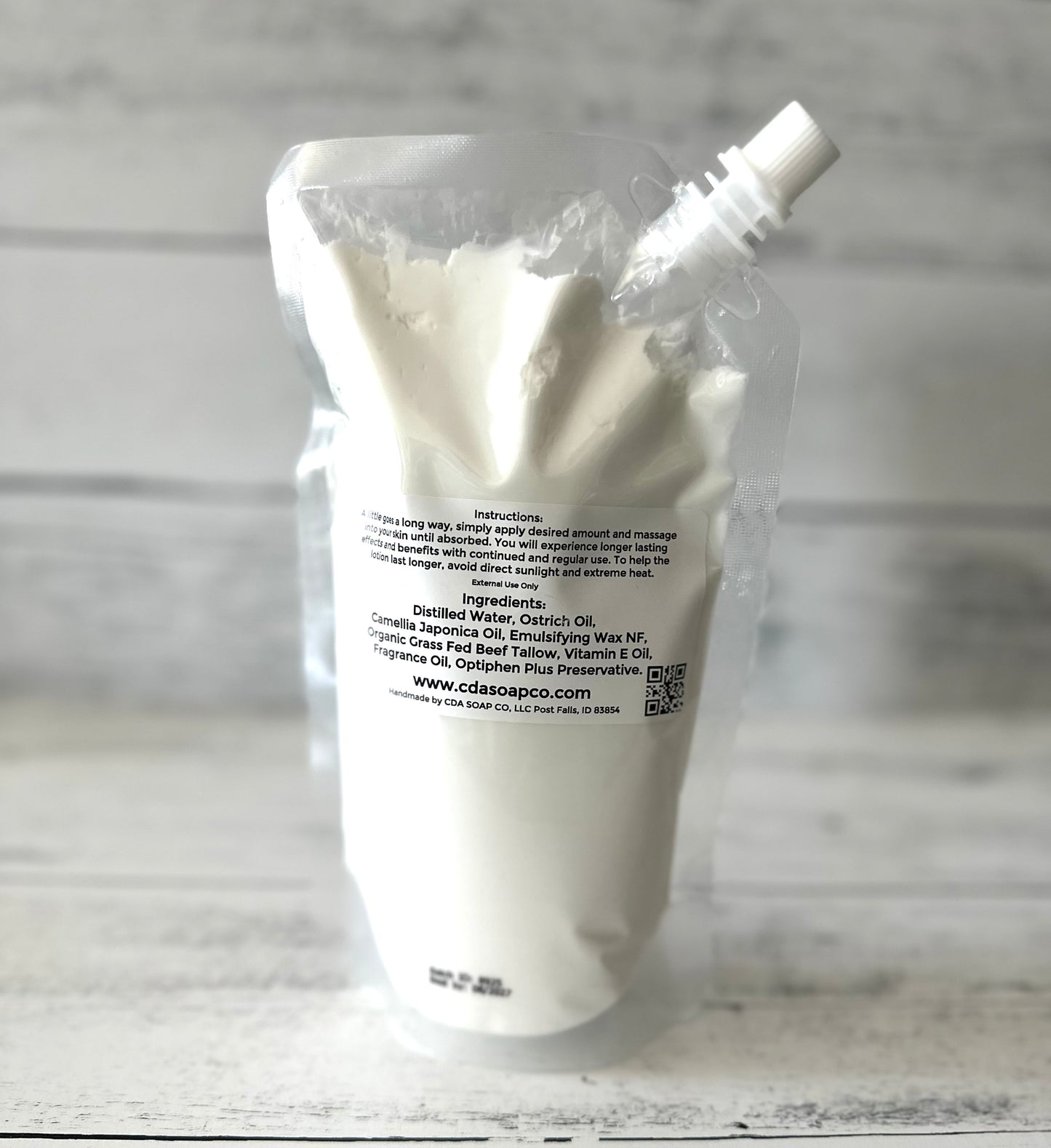 White lotion in a clear plastic packaging with a label on a wooden surface.