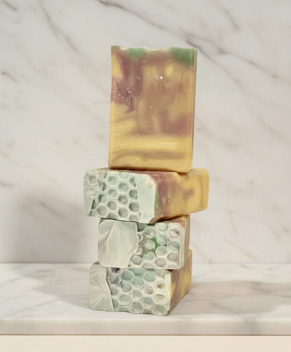 Stack of four handmade soap bars with natural patterns on a marble background
