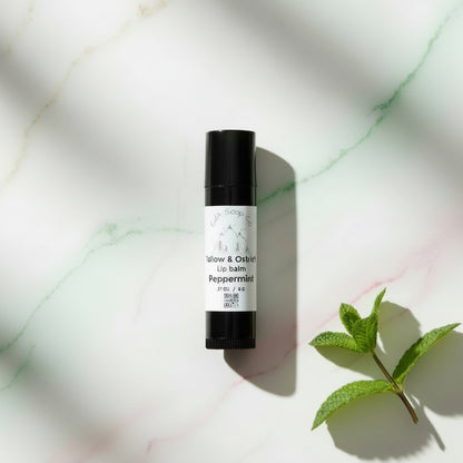 Black lip balm tube with a white label on a marble background with a Peppermint accent 