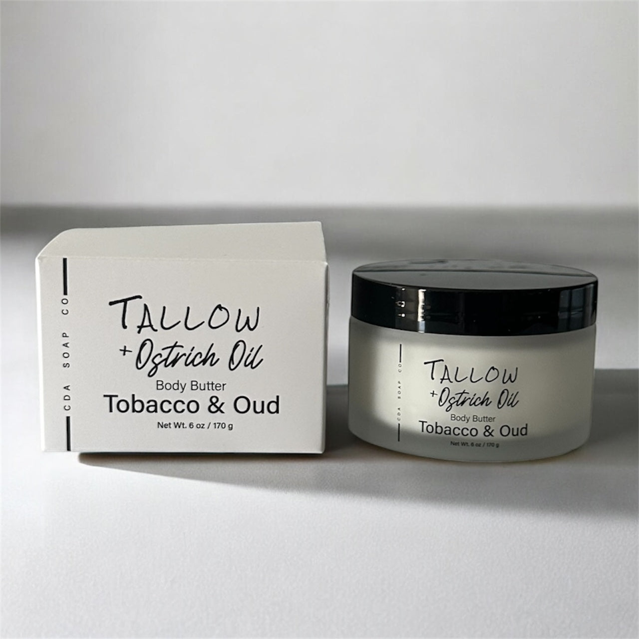Tobacco and Oud Tallow + Ostrich Oil body butter jar and packaging on a white background