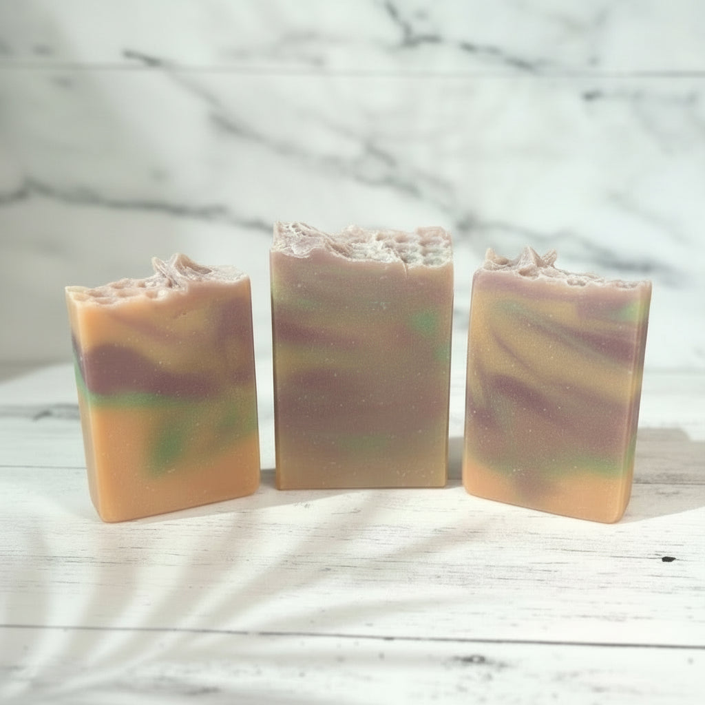 Three swirled soap bars on a wooden surface with a blurred natural background