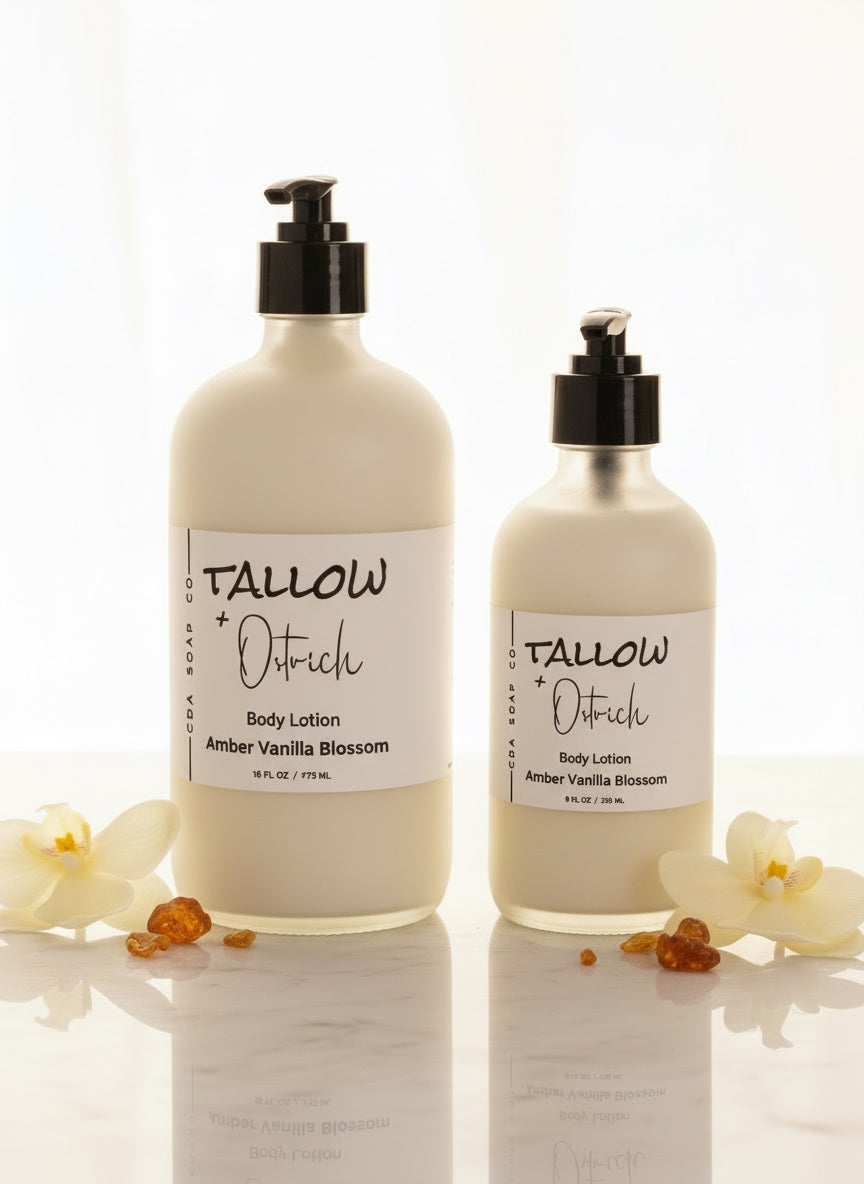 Two bottles of Tallow + Ostrich body lotion on a white background with flowers.