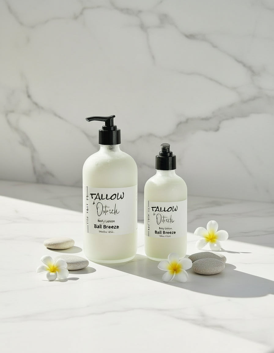 Two bottles of Bali Breeze scented Tallow & Ostrich oil CdA soap Co. body lotion on a white surface with flowers and towels