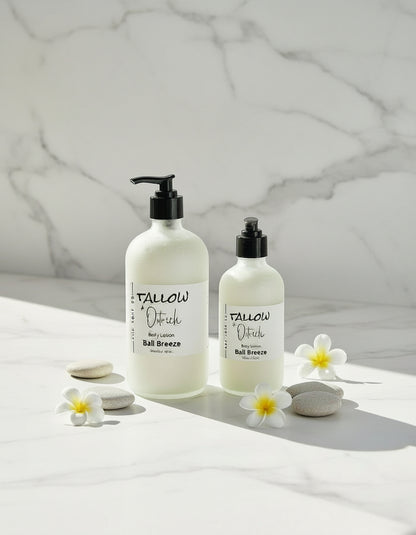 Two bottles of Bali Breeze scented Tallow & Ostrich oil CdA soap Co. body lotion on a white surface with flowers and towels