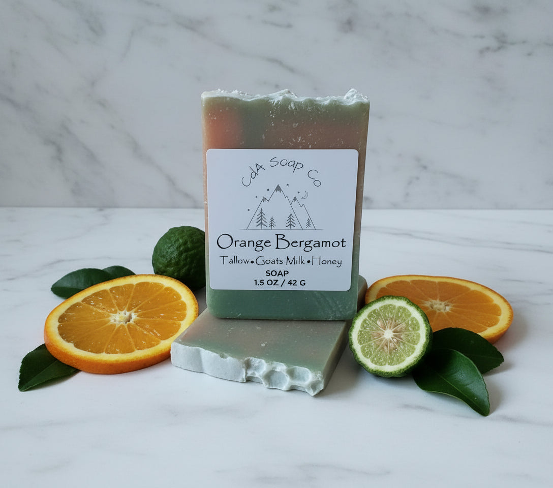 Bar of soap with 'CDA Soap Co' label surrounded by orange and lime slices on a marble surface