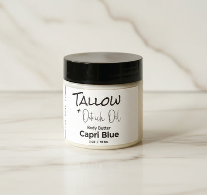 a jar of capri blue tallow body butter white marble background