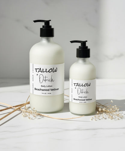 Two bottles of Tallow & Ostrich body lotion on a light surface with dried plants.
