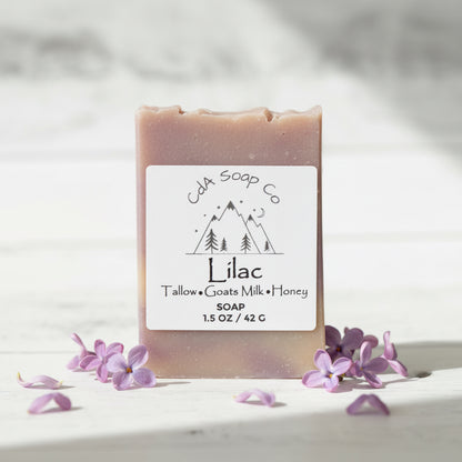 Bar of lilac soap with a CDA Soap Co label on a white background with lilac flowers.