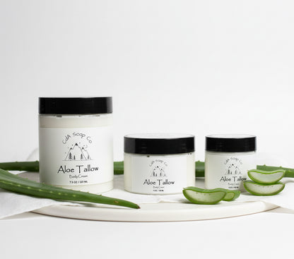Three jars of Aloe Tallow body cream on a white background with aloe vera leaves.