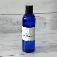 Blue bottle of Aloe Chamomile facial toner on a wooden surface